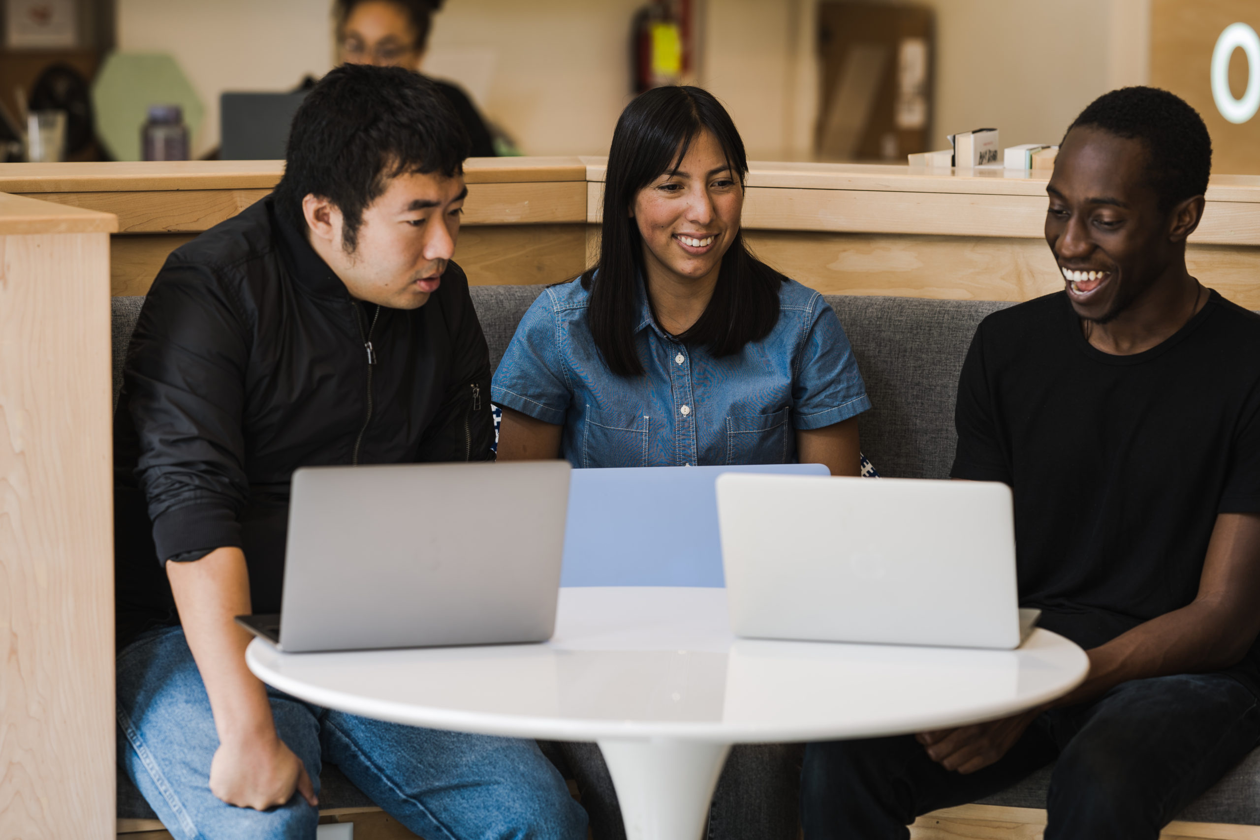 three people with laptops working at a table